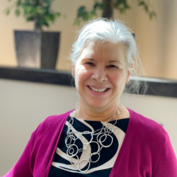 Kathy DeHaven, Executive Director at Cedar Ridge Village, smiling in a professional setting, wearing a purple cardigan and statement necklace.