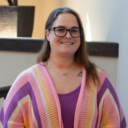 Denni Gale, Business Office Manager at Cedar Ridge Village, smiling in a colorful cardigan with a light background.