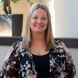Kim Allen, MDS Coordinator at Cedar Ridge Village, smiling in a floral blouse against a softly lit background.