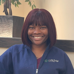 Barineka Naenwi-Befii, Infection Control & Quality Assurance Nurse at Cedar Ridge Village, smiling in a navy blue jacket with the Cedar Ridge logo.